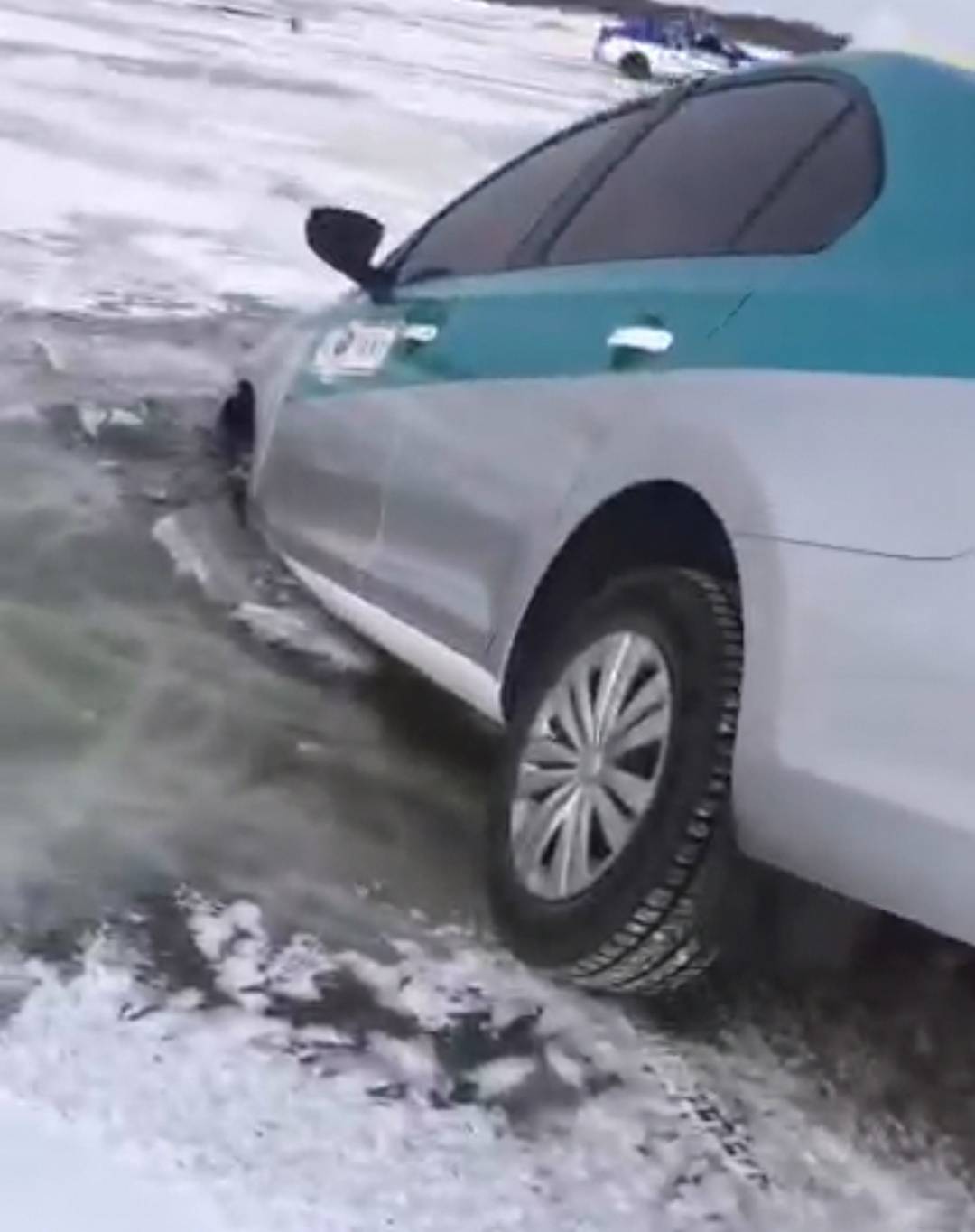 出租车的三个轮子都陷在了冰窟窿里,车头已经浸在了水里