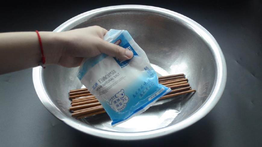 首先把新买的筷子拆开放进盆子里,并且往筷子上倒点食用盐