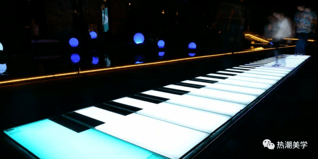 墙面用简约的科技灯光线条贯穿首尾,地面装置音乐互动钢琴键连接