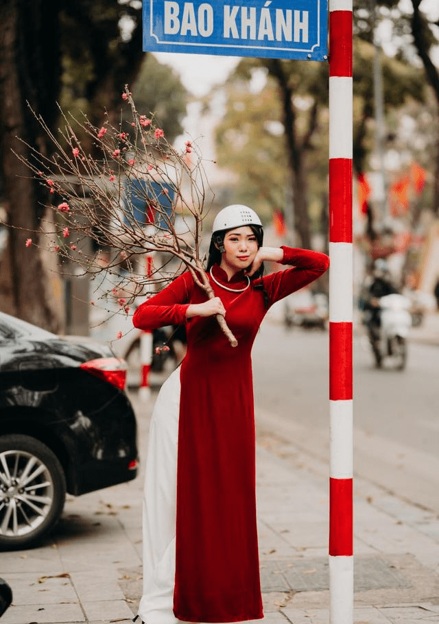 身穿红色奥黛,手持桃枝的越南姑娘,举手投足之间,甜美