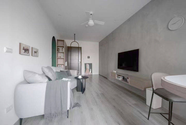 灰泥电视墙面和灰色木地板颜色相呼应,整体简洁大方,宽敞明亮.