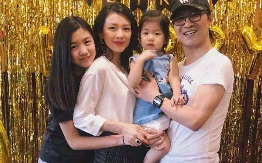 汪峰身着黑色t恤,忙前忙后拎包抱孩子,全家人穿着家庭装