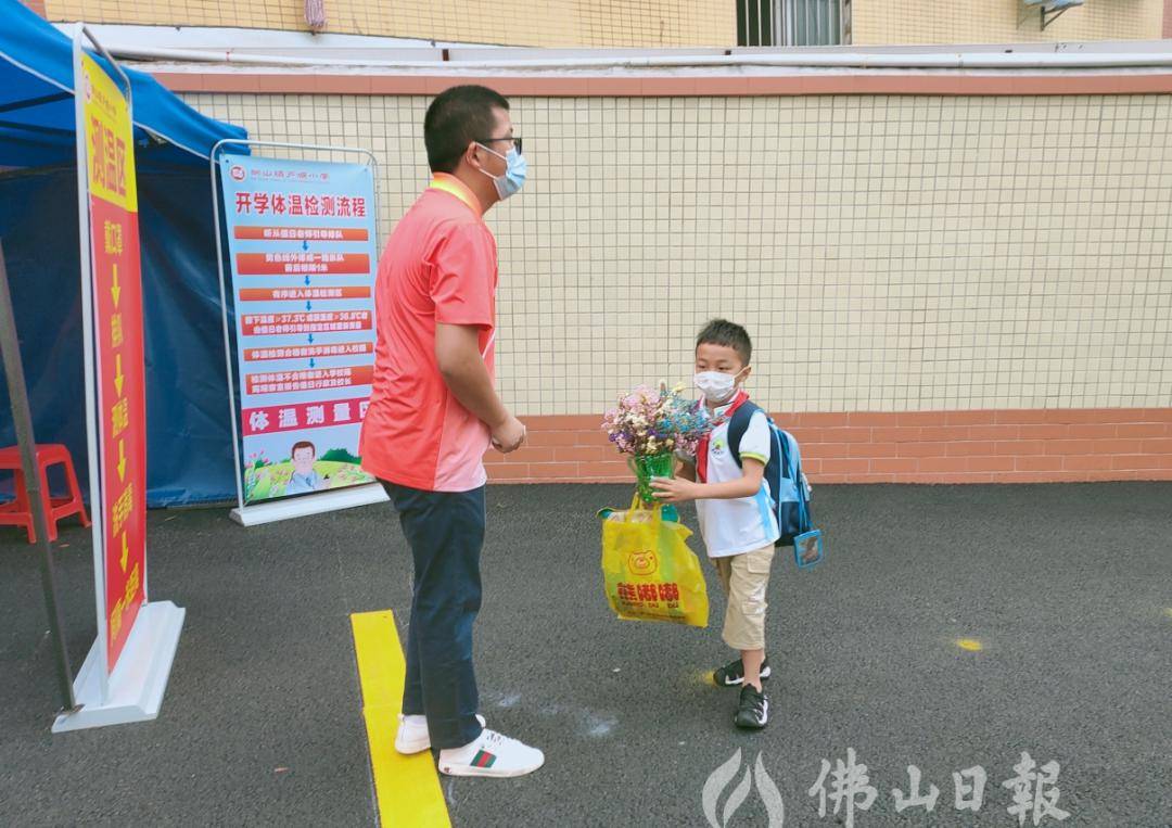 "在狮山镇芦塘小学,一位学生捧着一盆鲜花返校.