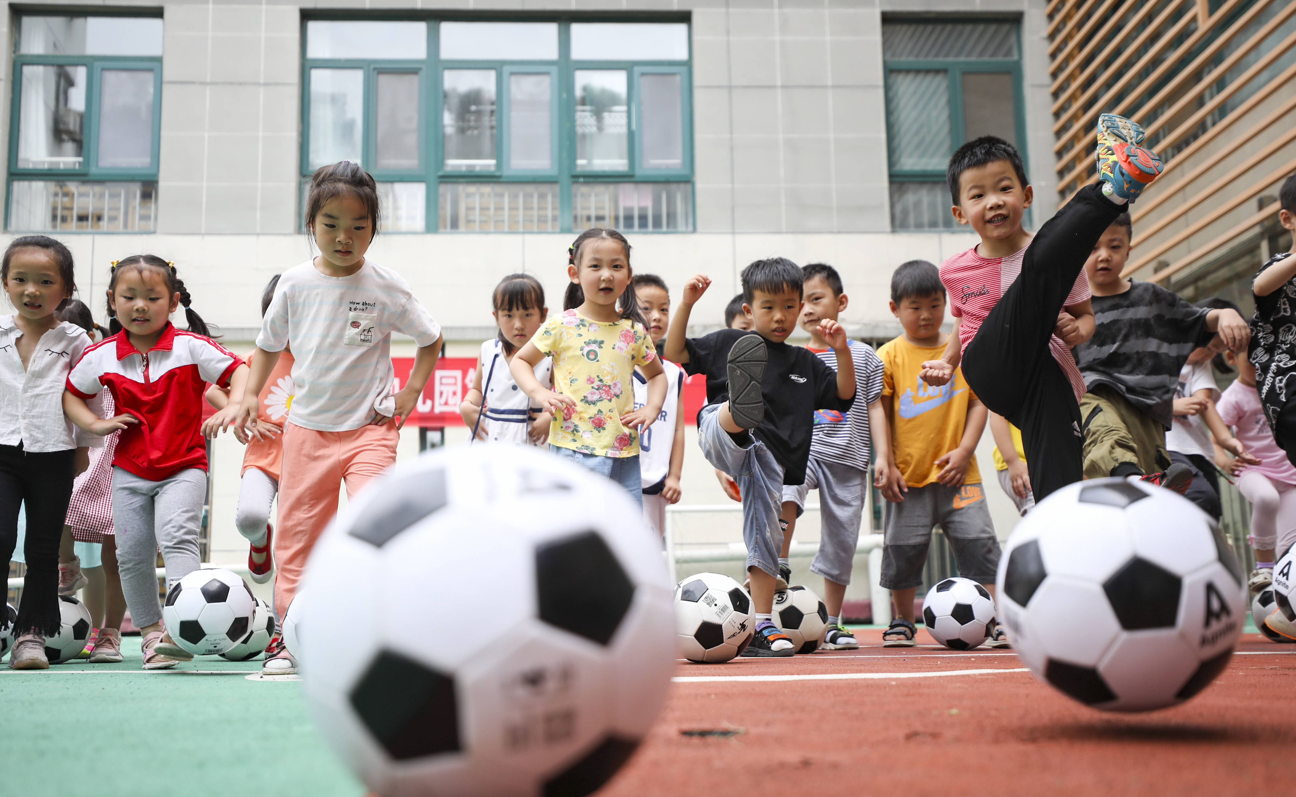 7月14日,幼儿园小朋友在踢足球.