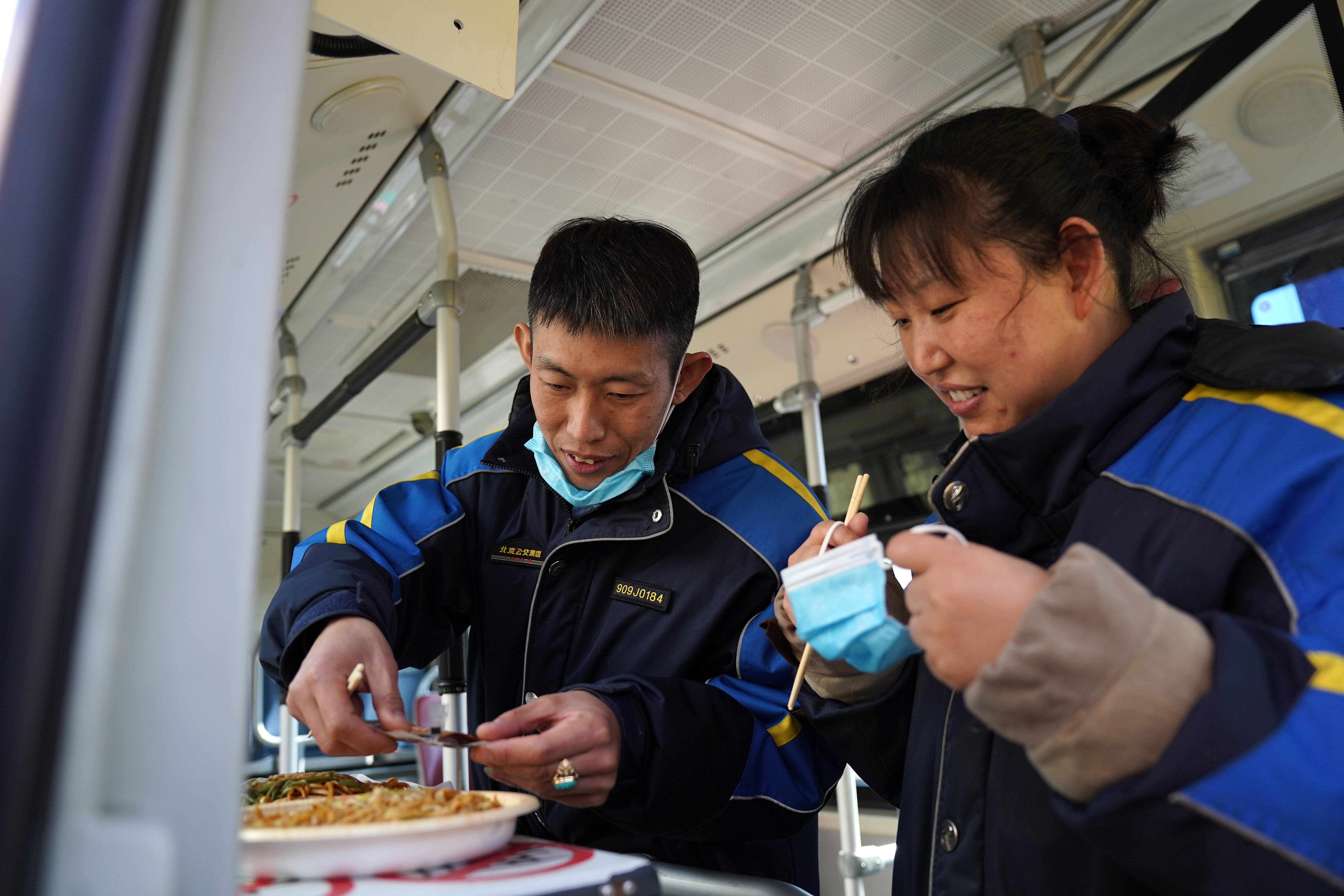 在地铁建国门站,姜楠(左)和柴丽莉在公交车上一起吃午饭(2月10日摄.