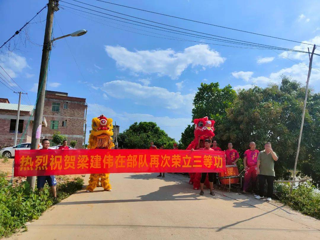 乡亲们拉着"热烈祝贺梁建伟在部队再次荣立三等功"横幅,一路敲锣打鼓