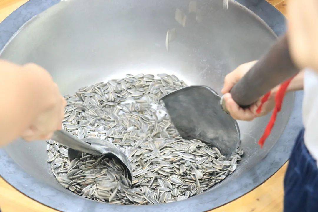 我们去打谷粒吧"在老师的协助下,这边的同学在大铁锅前炒起了瓜子