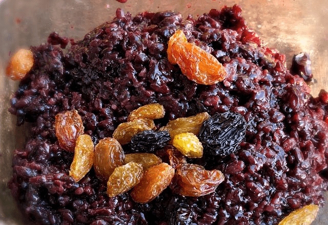 蒸好的黑米,取出一部分,不热时放入一把葡萄干,稍微混合一下,黑米馅就