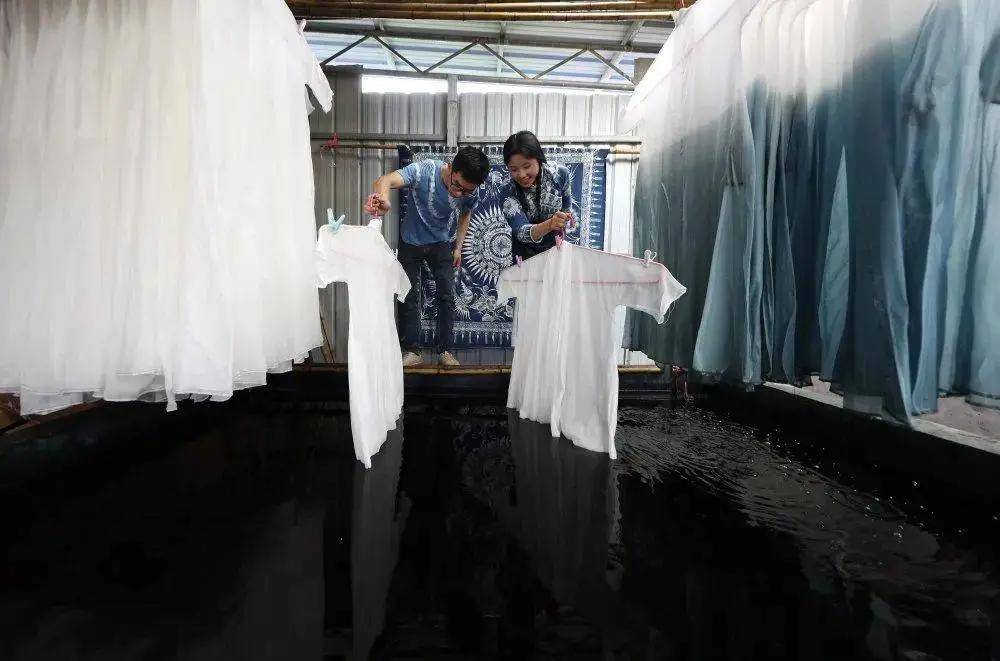 潘其波(左),刘绍花在染坊里浸染服装产品