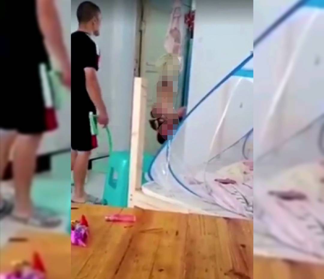 根据视频显示,一名10岁左右的男孩被父亲倒吊在家里的门框上,孩子的