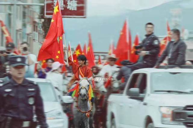 民族|丁真骑白马上街超有排面!穿藏袍举国旗意气风发,笑容好有感染力