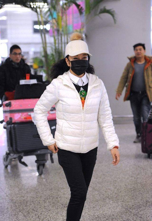 粉色 62岁刘晓庆现机场，蹦蹦跳跳心情大好，穿白色羽绒服少女感十足