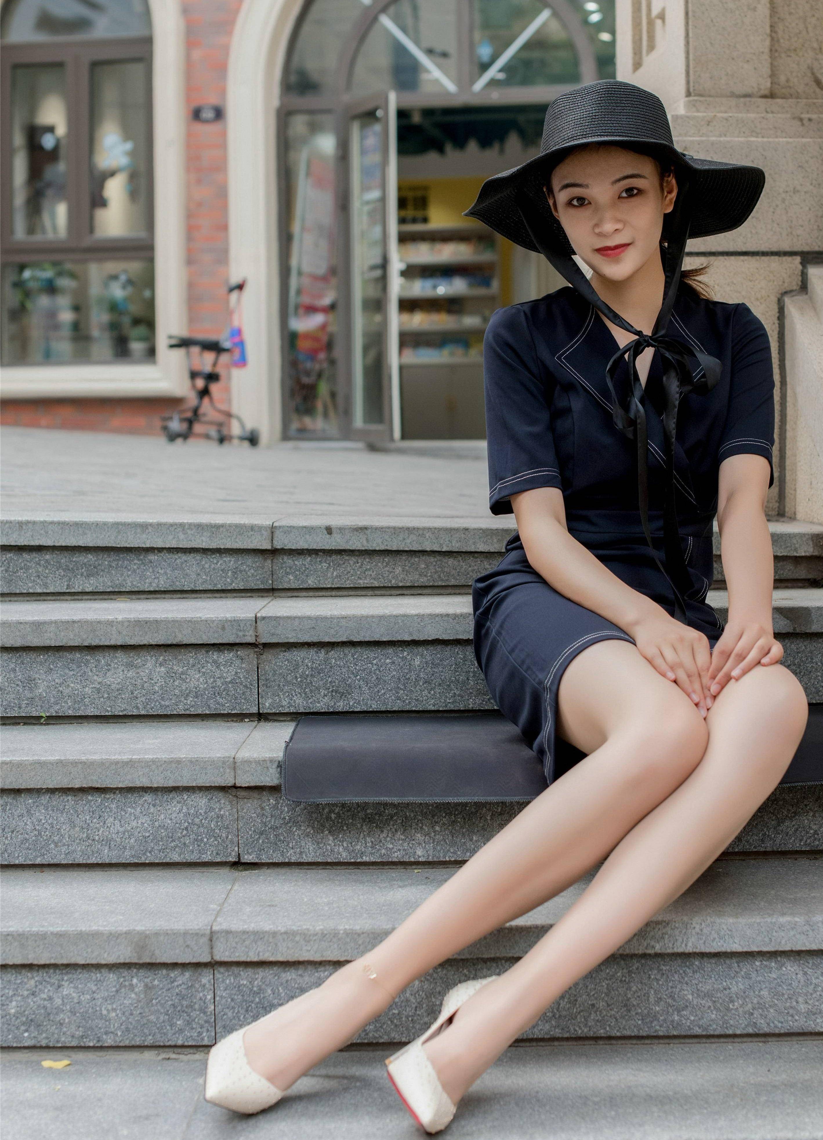 头顶遮阳伞帽,身穿西装连衣裙,脚穿尖头高跟鞋,干练