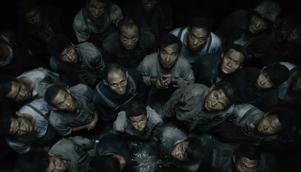 一群衣衫褴褛,灰头土脸的人抬头看向镜头.