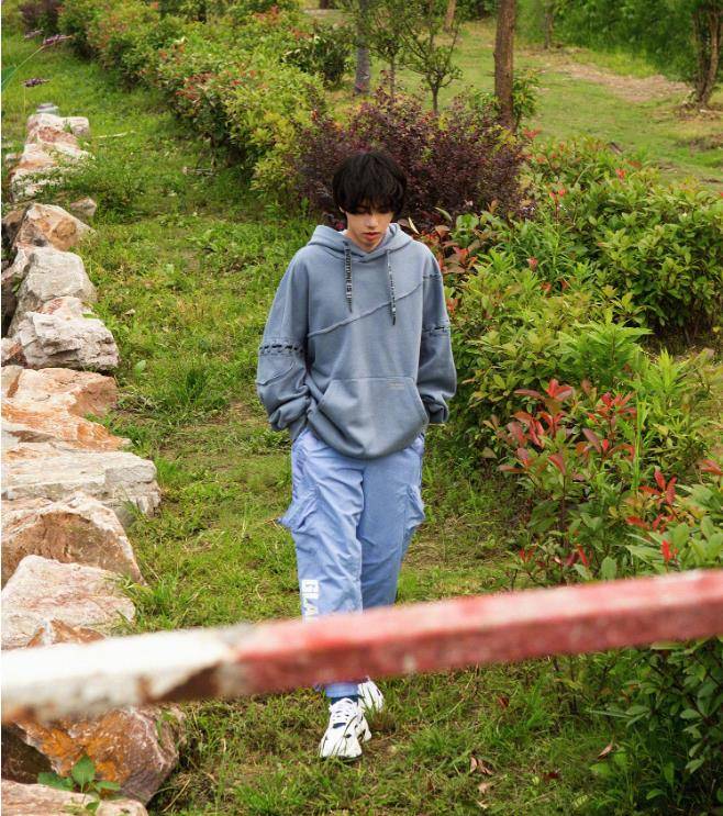 当爸爸之前的华晨宇是孤单的,他穿着灰色连帽卫衣独自走在绿色的草地