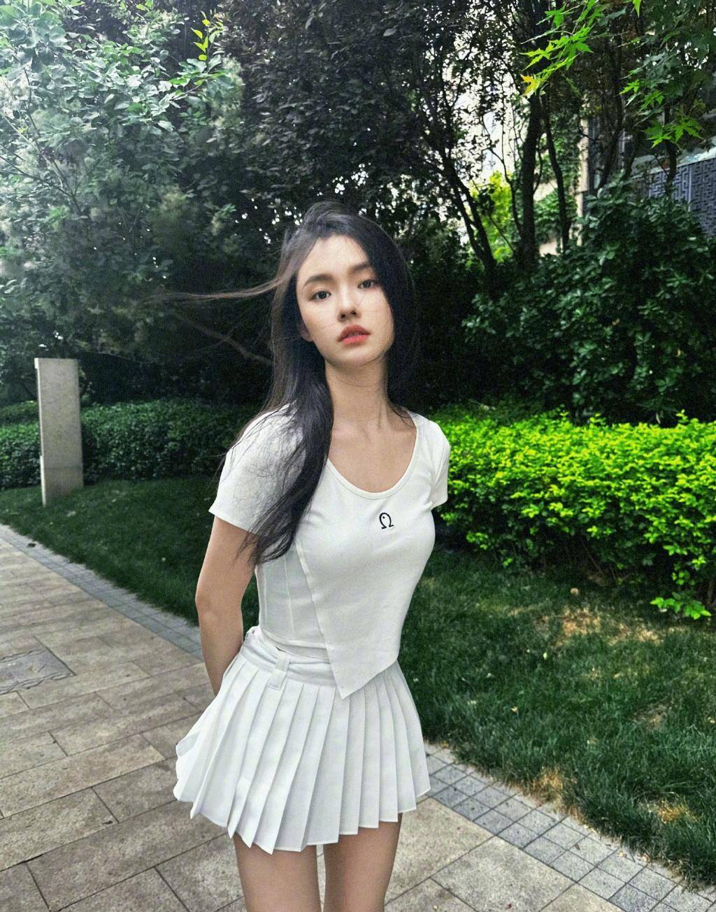 女演员林允分享了一张身穿白色连衣裙在草地上拍照的照片,青春情怀