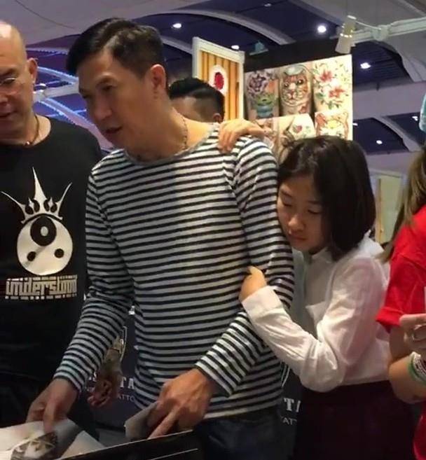 张家辉于一家纹身店挑选纹身图案,爱女亦随行.