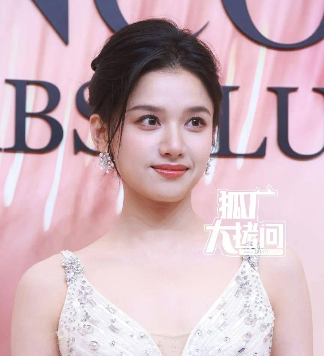 张婧仪身穿深白色v领连衣裙,将头发扎成发髻,简单又清爽.