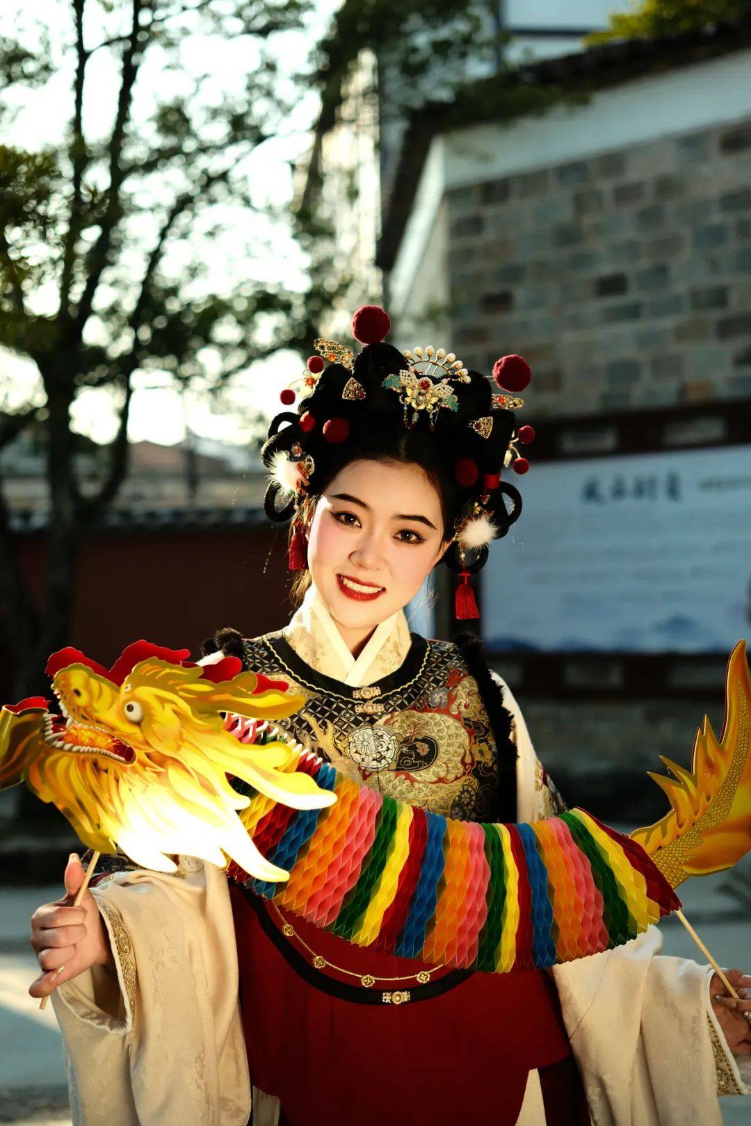 广场有个大戏台广场两边挂满了红灯笼还有一颗挂满红丝带的许愿树这