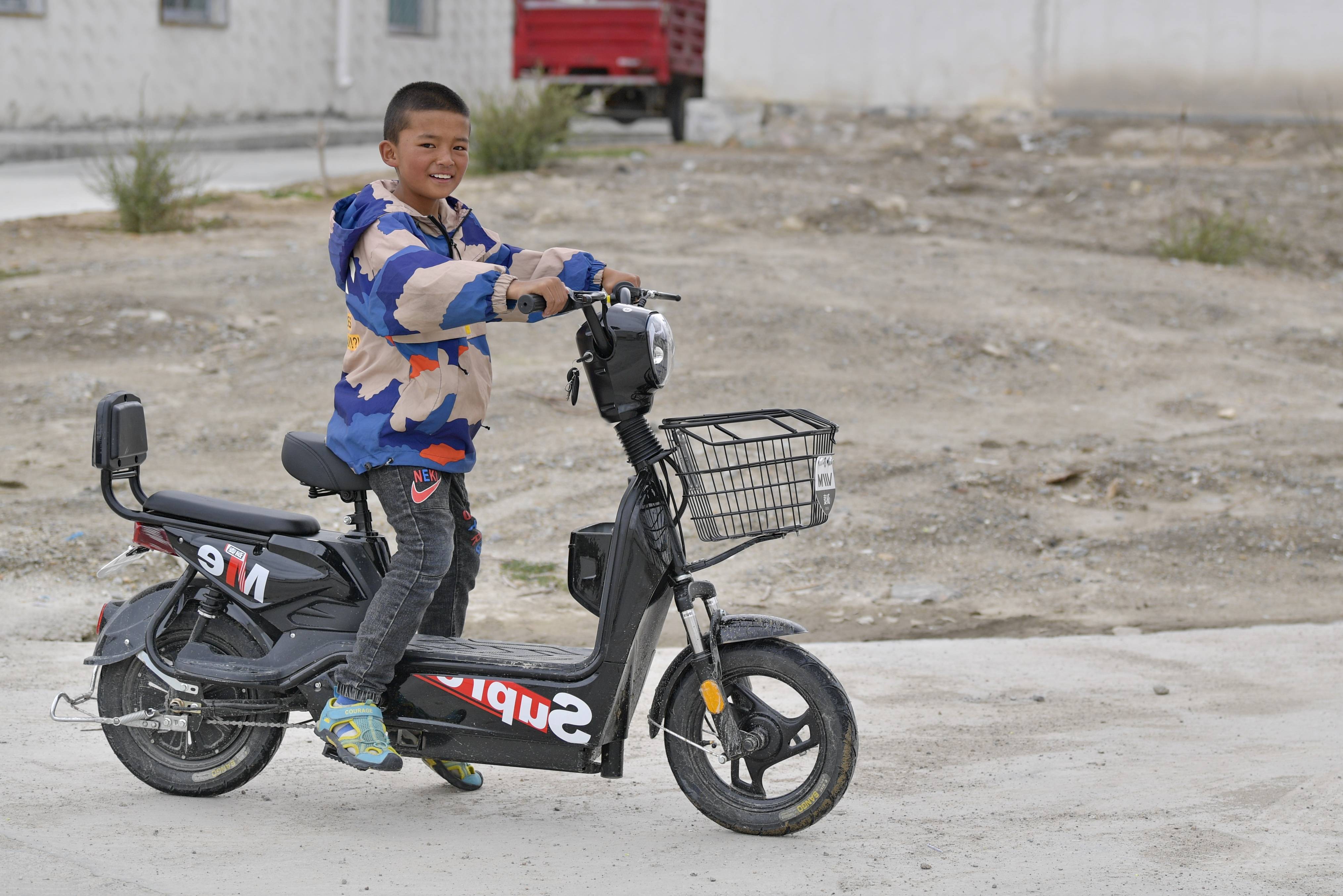 一名小学生在彩渠塘村骑电动车(8月2日摄)