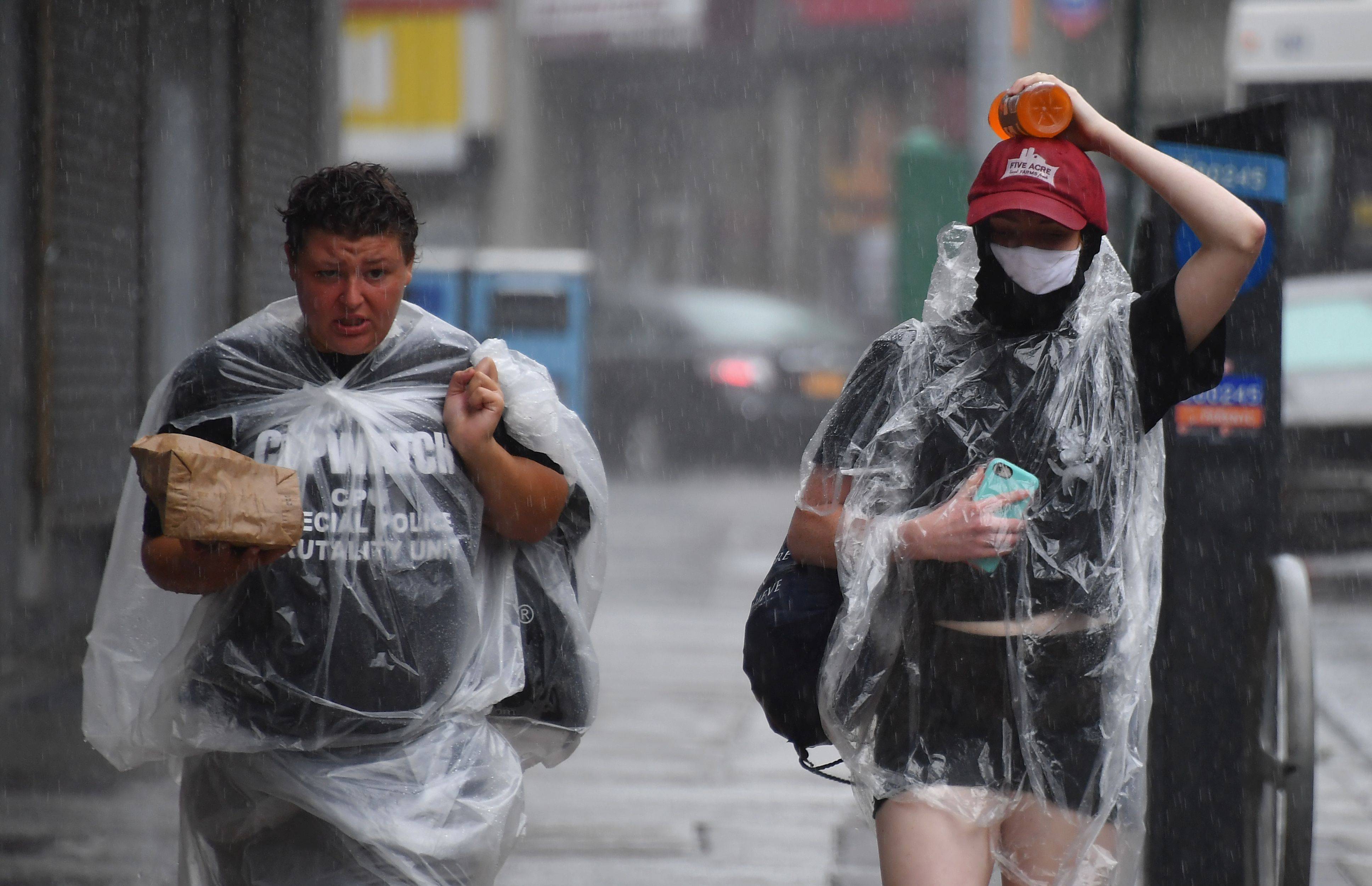 8月4日,行人在美国纽约冒着风雨出行.