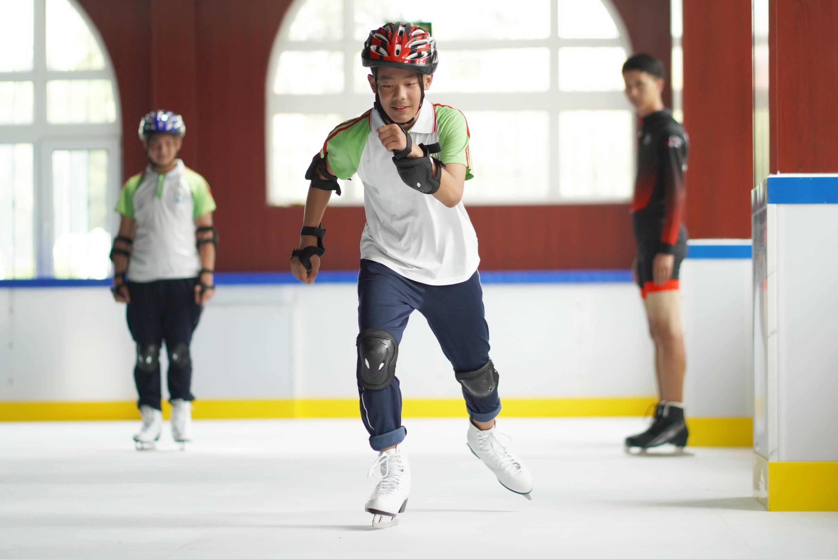 8月9日,在河北省邢台市内丘县滑冰馆,一名学员(中)在练习滑冰基本动作