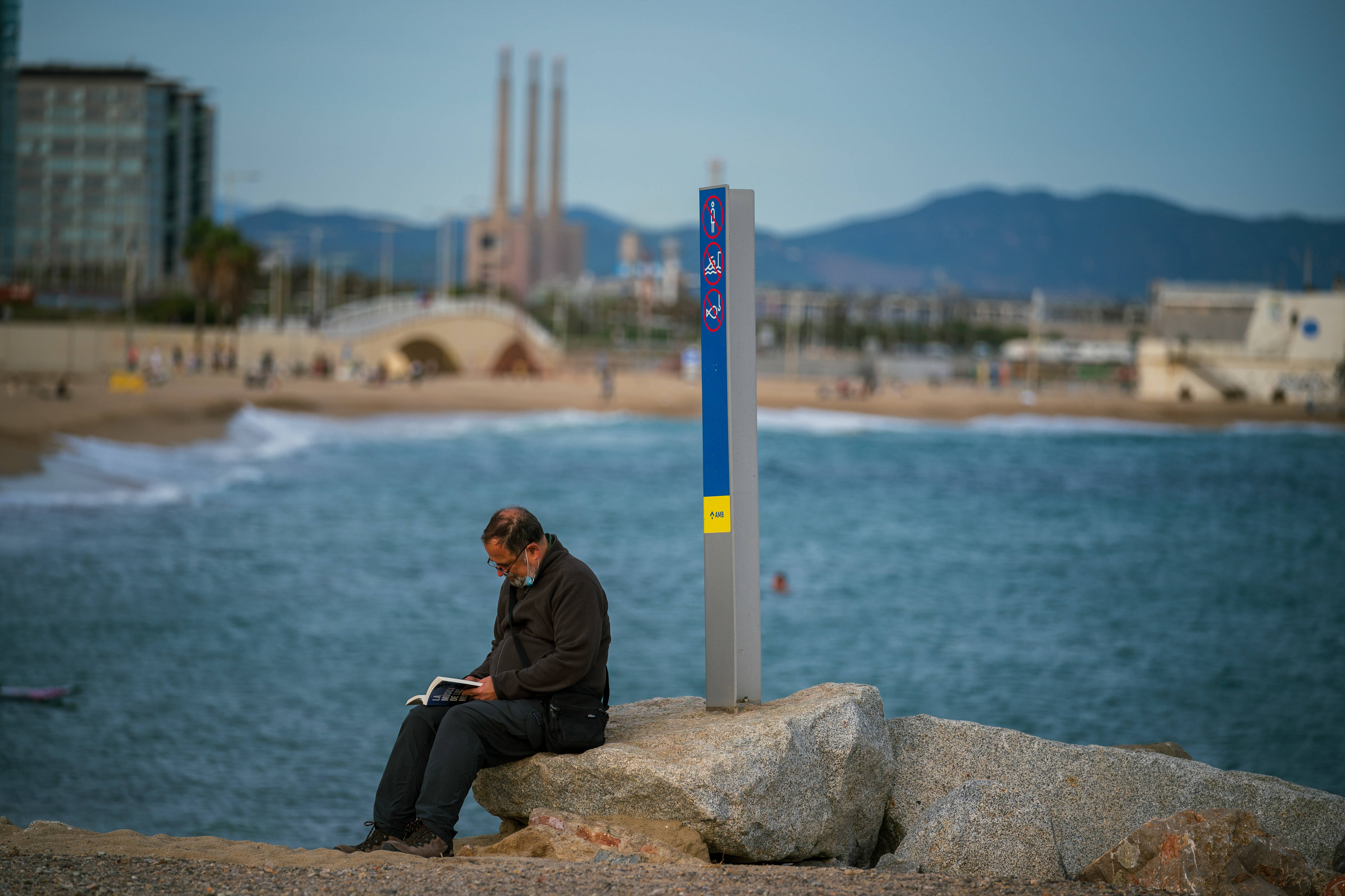 10月25日傍晚,一名男子在西班牙巴塞罗那海边读书.
