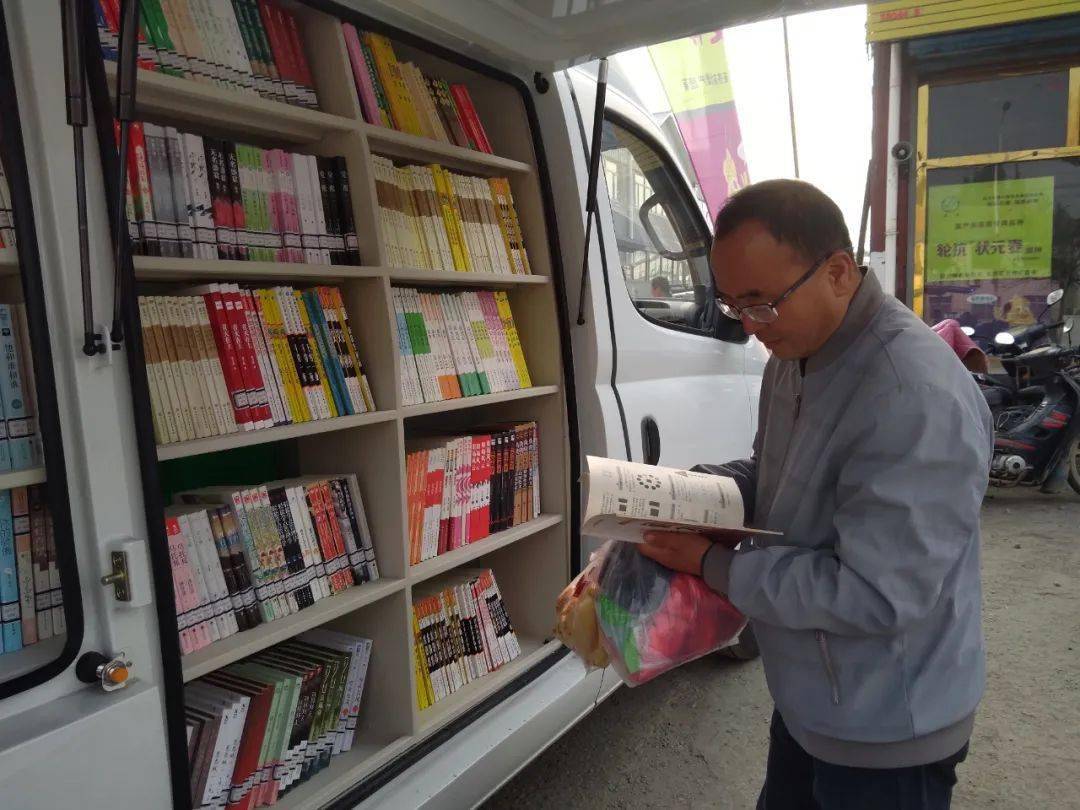 一个小型移动图书馆,里面崭新的书架排列两侧,载有中外文学,历史传记
