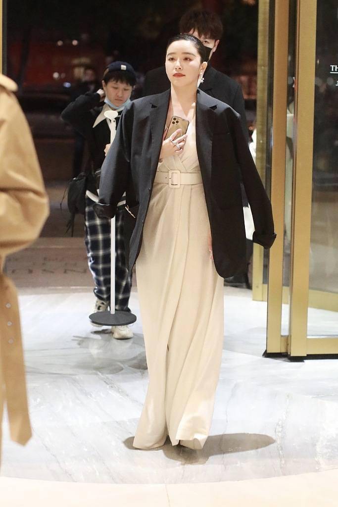 近日,阚清子现身某酒店,她身穿白色礼服披着黑西装外套御寒,用手捂着