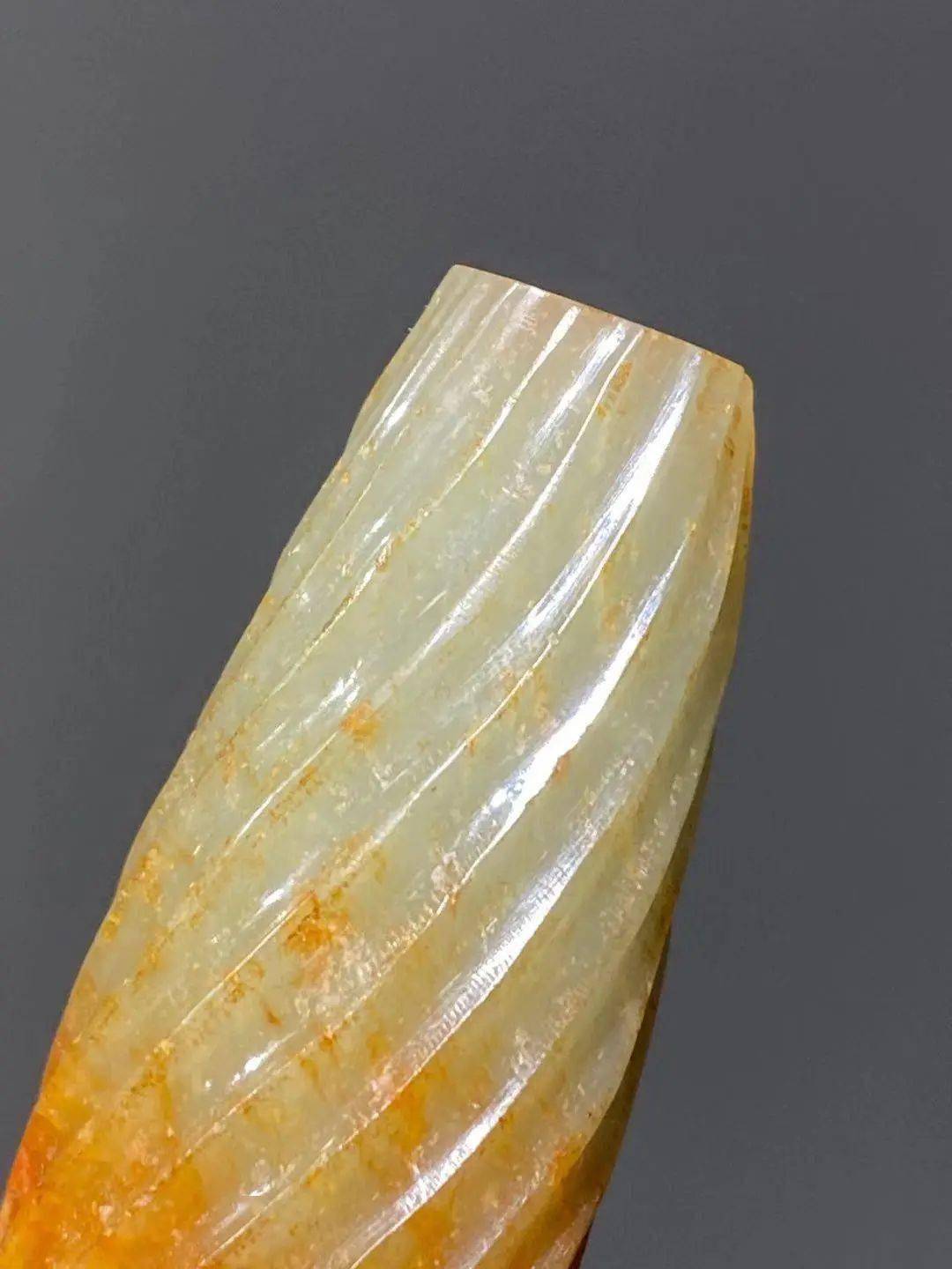 此白玉雕橄榄型勒子表面浅浮雕绞丝螺旋纹,垂直钻穿线孔,略带淡青黄