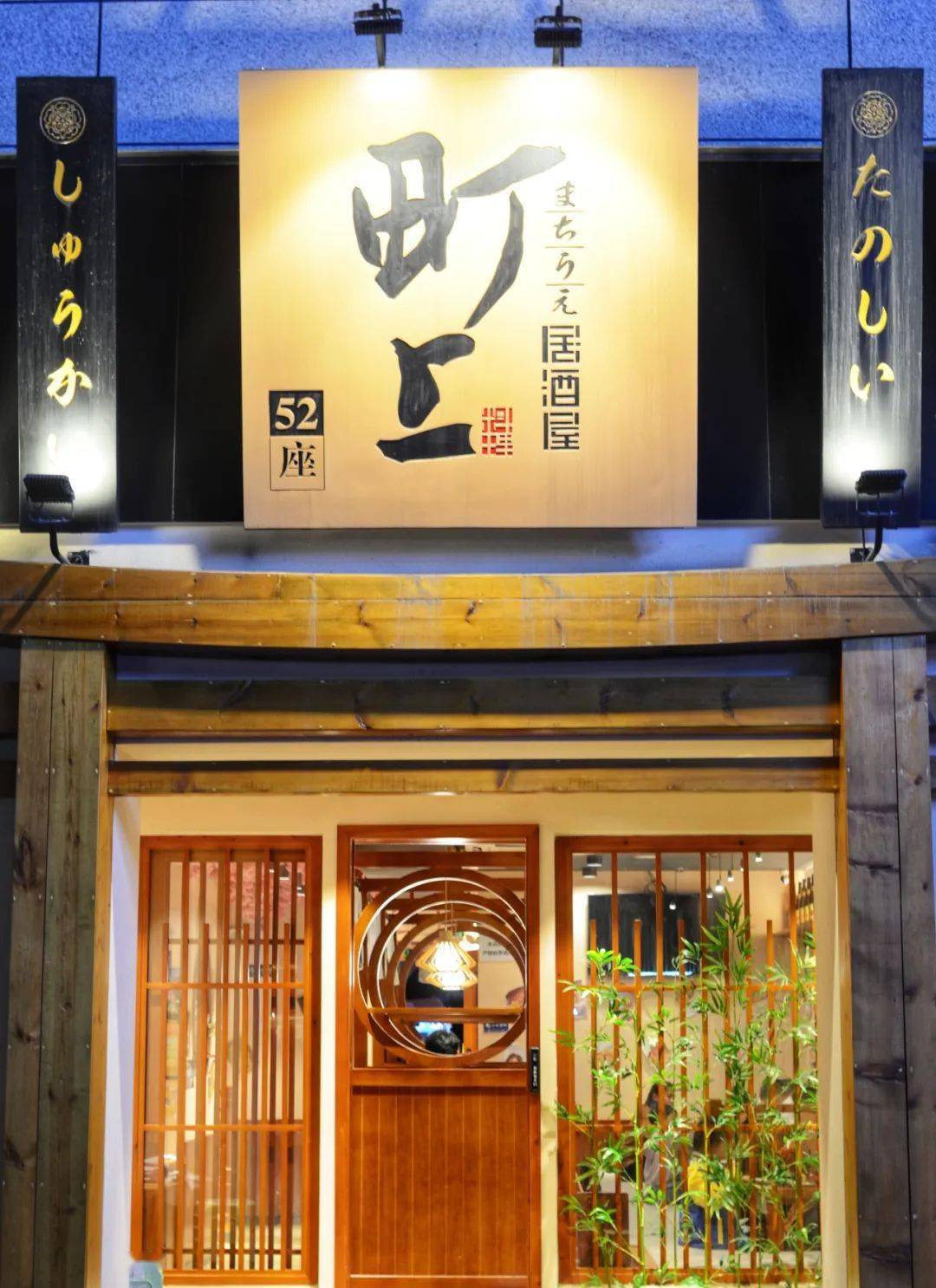 实木门框,黑色日文牌匾与中央招牌浑然一体,此外还配置了日式灯笼,泛