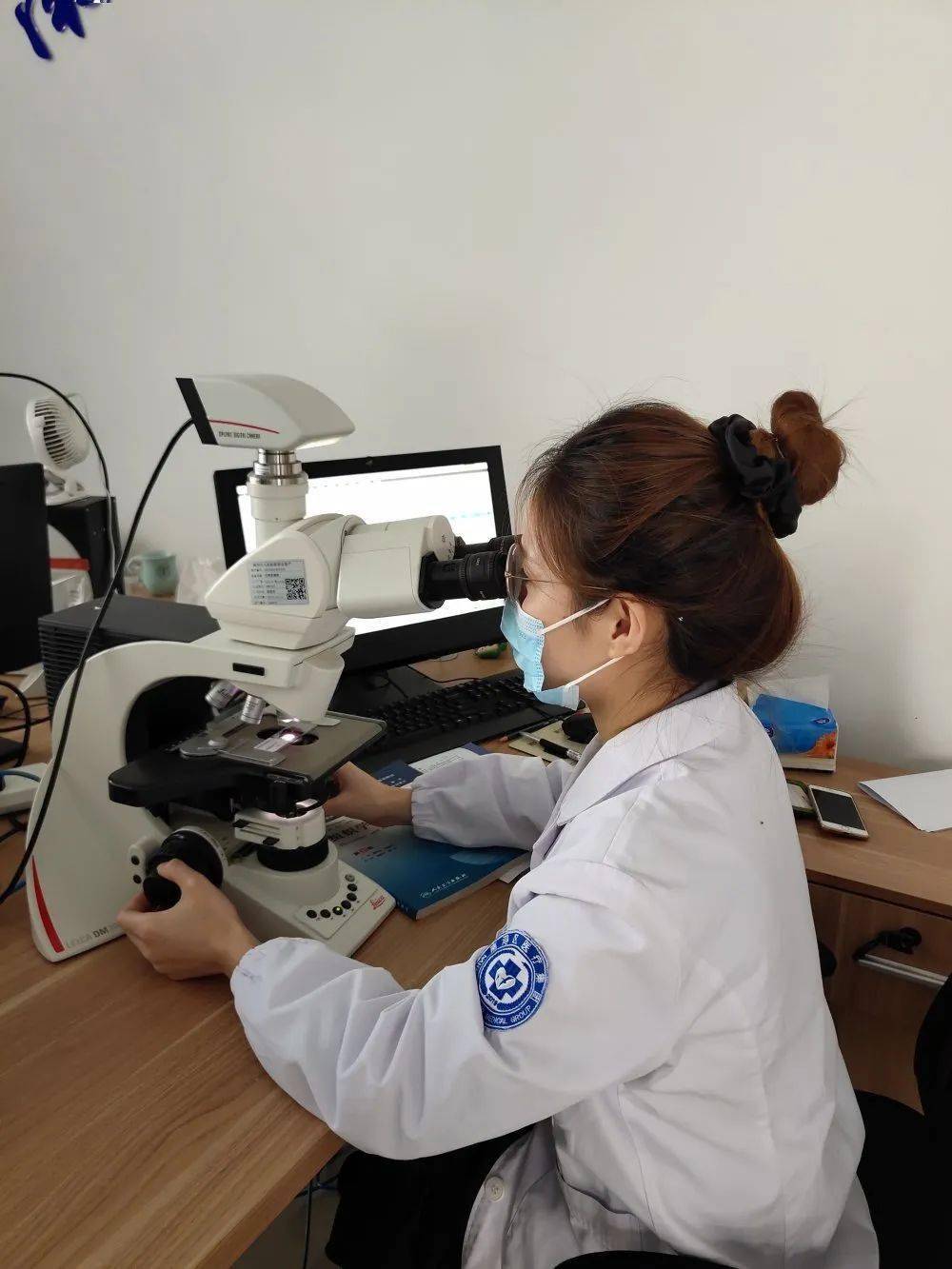 病理医生用显微镜观察切片,参考申请单上描述的患者基本情况,综合分析