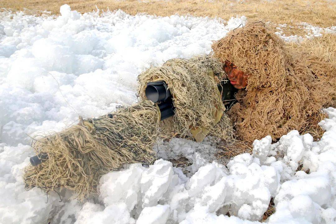 2名身着吉利服的狙击手,爬在冰冷的雪地里纹丝不动,脸颊冻得通红.