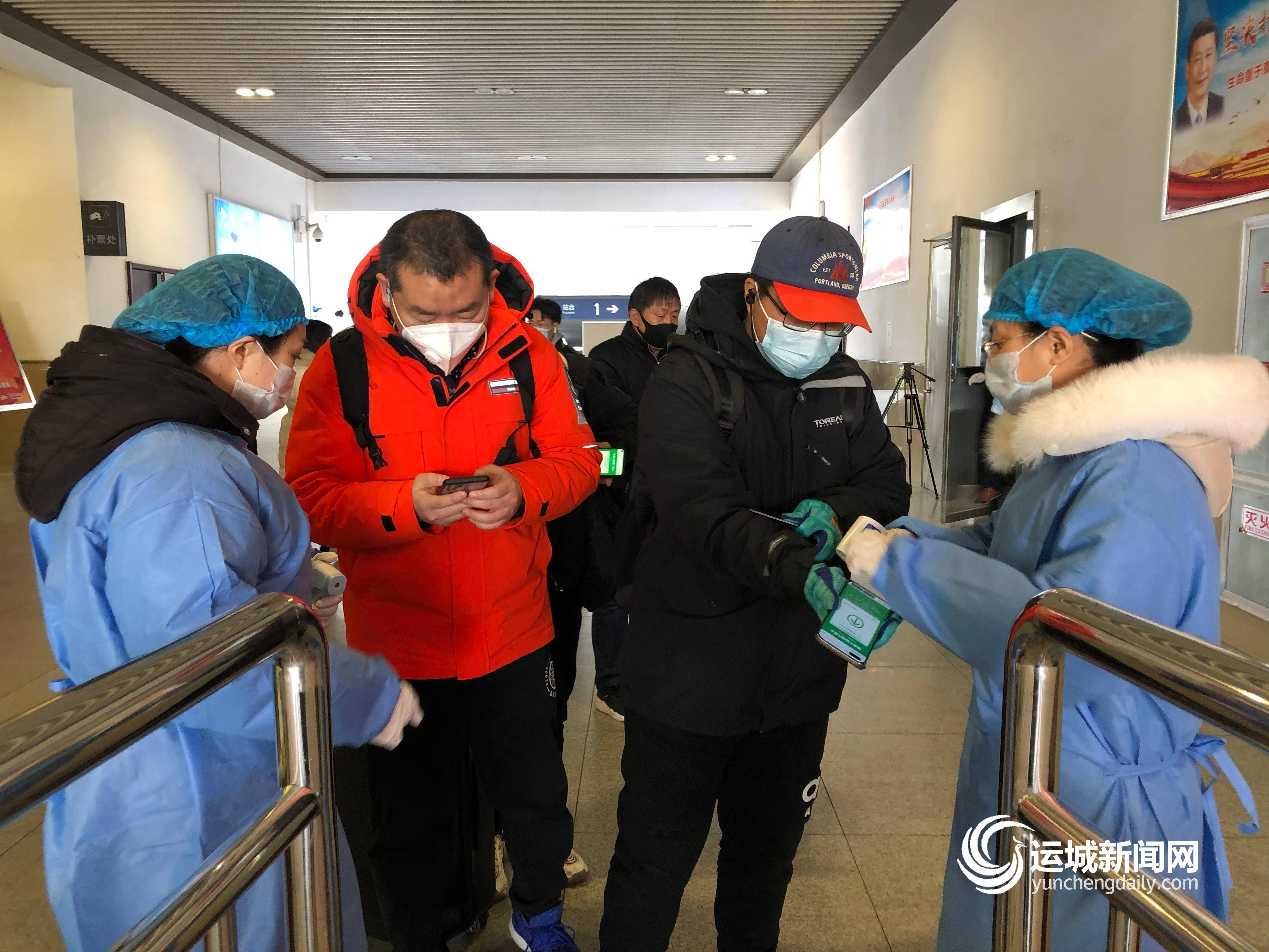 志愿者在运城北站出站口引导乘客扫码登记行程并测量体温 冯杨婕 摄