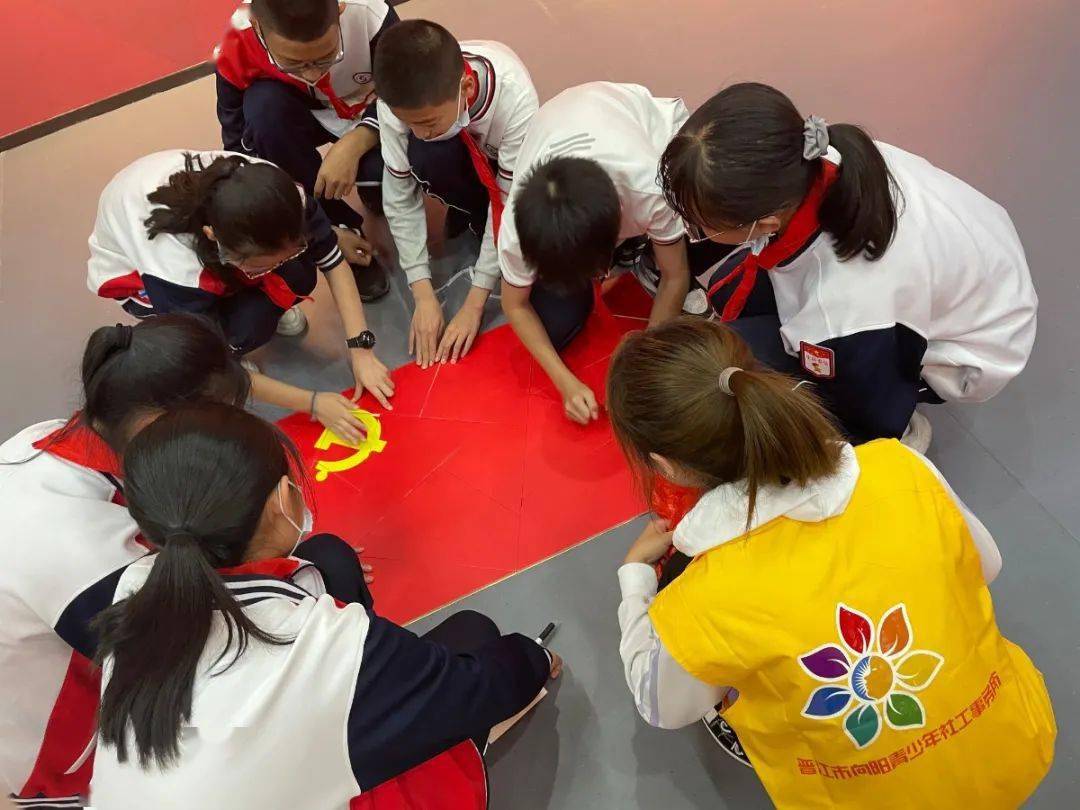 青少年们将获得的党旗拼图碎片汇集在一起拼成鲜红的党旗,随后手执