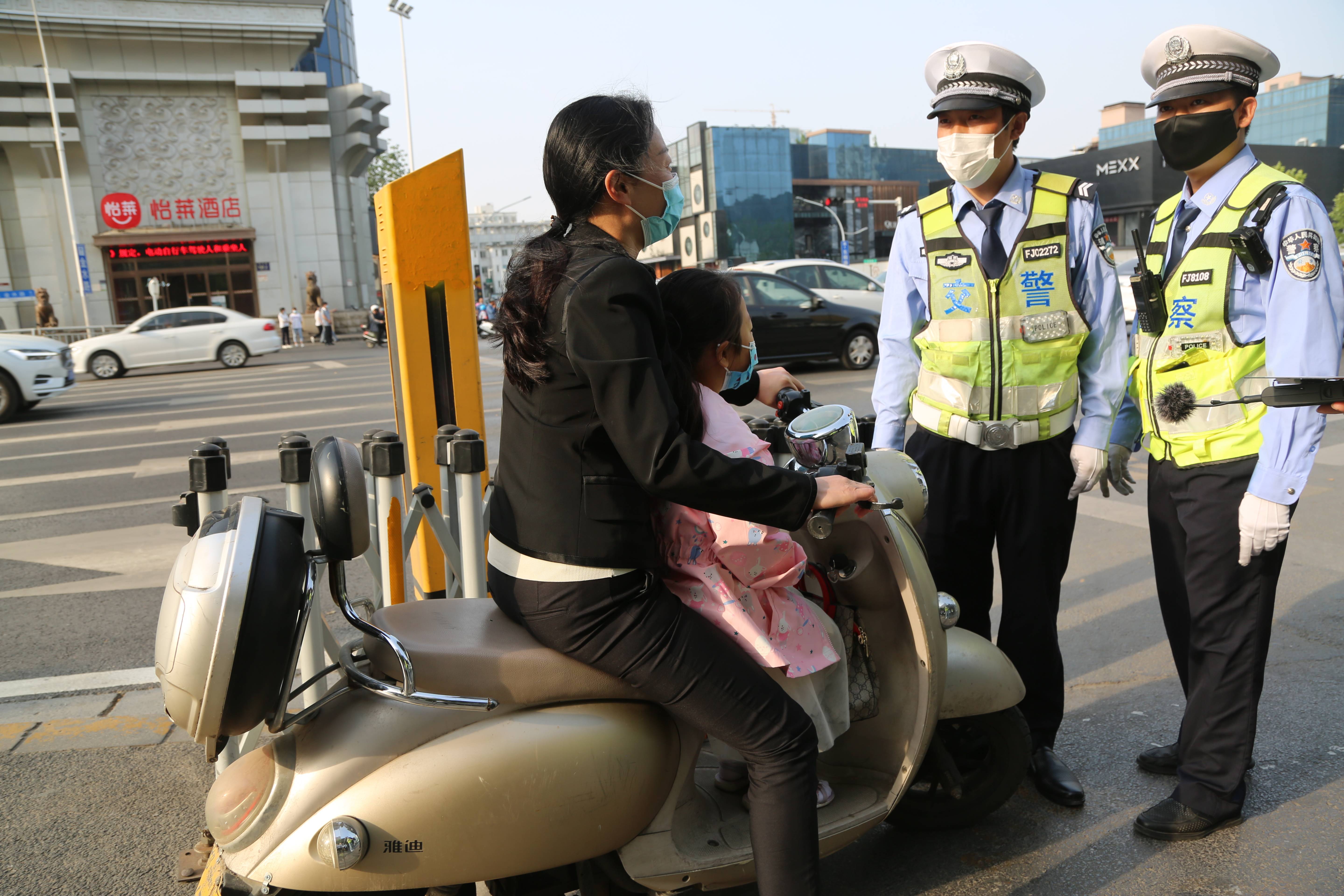 街头骑电动车戴头盔已成主流但不规范佩戴仍存在安全隐患