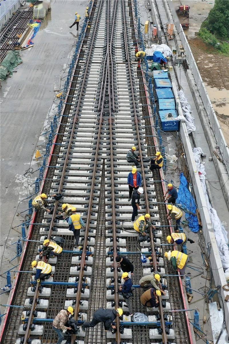 宽阔的高架桥面上,一组道岔铁轨已经铺设完成,工人正在进行浇筑前的