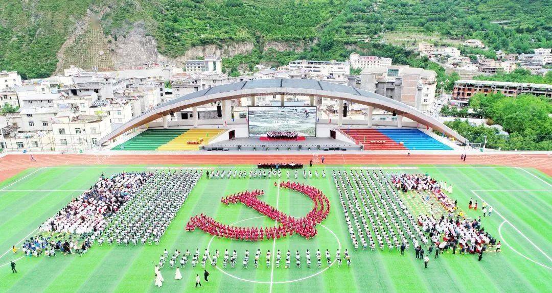 在九寨沟县七一南坪中学操场上,学生们自发组织拼成党旗图案,挥舞着手