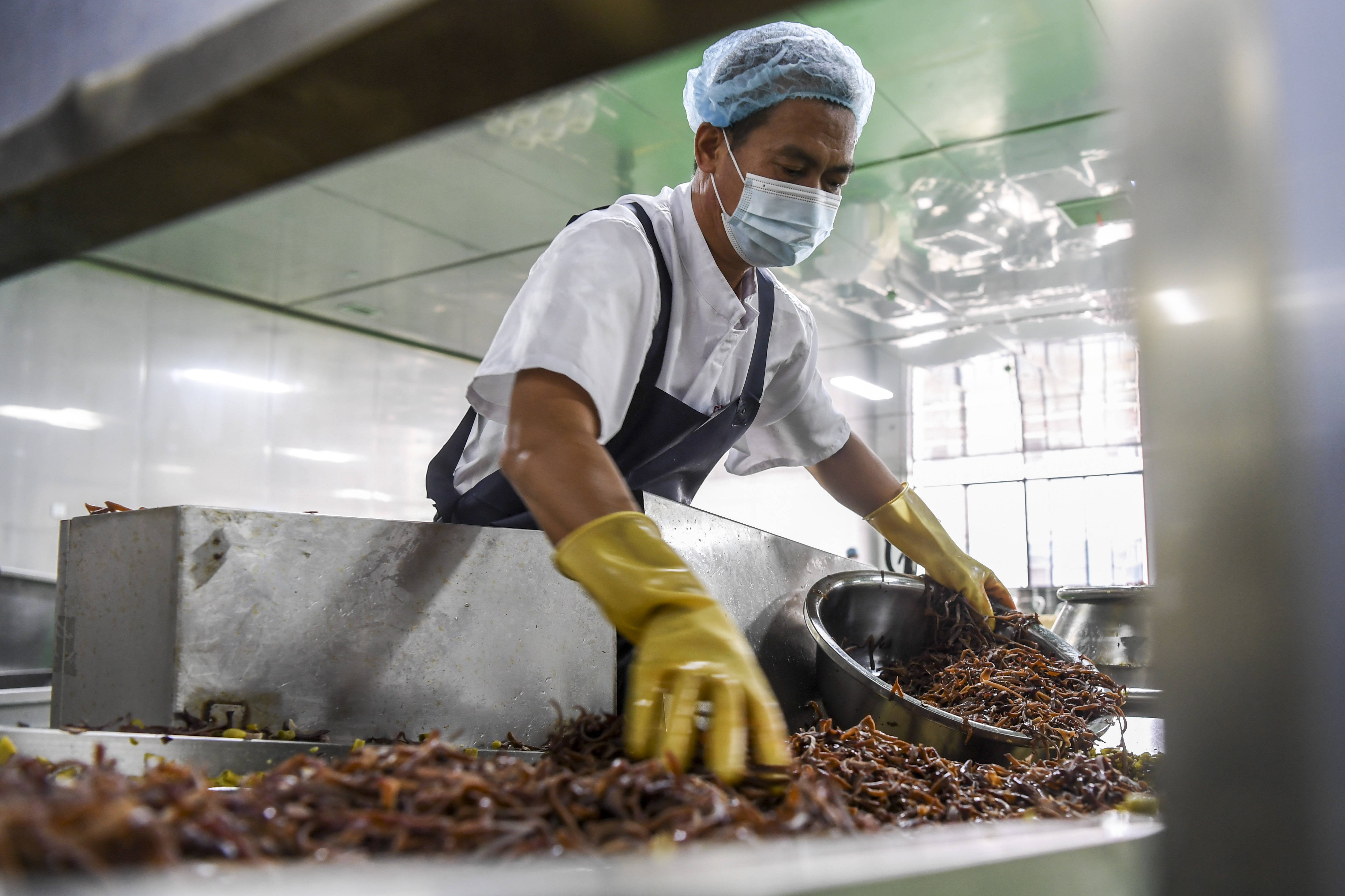 6月11日,广西柳州市一家螺蛳粉生产企业的工作人员将螺蛳粉配料送上