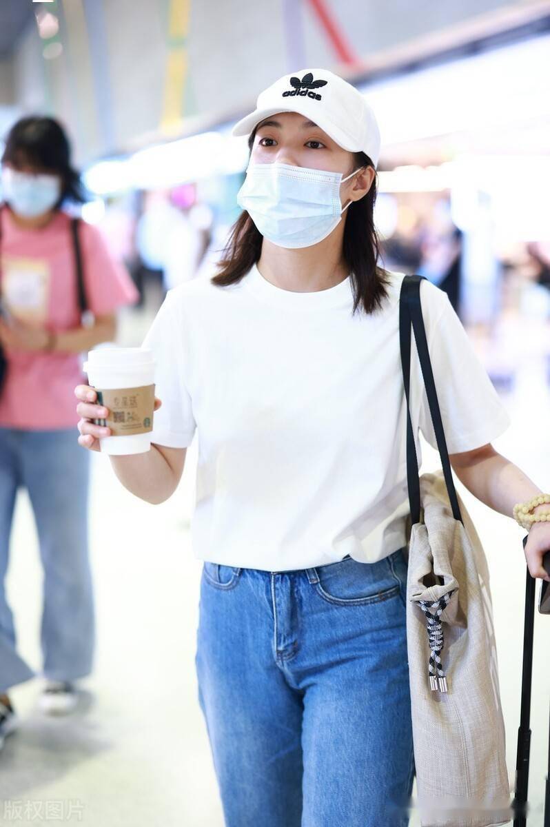 张雅钦身穿白t搭配牛仔裤干净清爽,斜背帆布包手拿咖啡十分悠闲