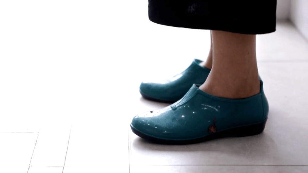 脚上套着一双雨鞋花t恤外罩着蓝色工作服歌者的服装很醒目嗯嗯,不错哦