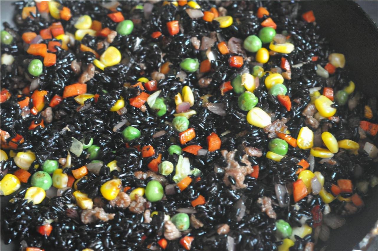 炒香至六七成熟,加入蒸好的黑糯米饭翻炒,饭内加点猪油会更香哟,加入