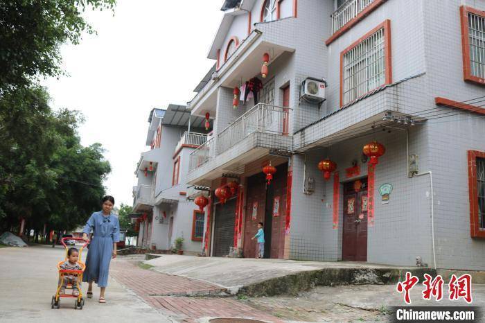 在平果市新安镇道峨村下甫新村,妇女推出婴儿车在村里散步.