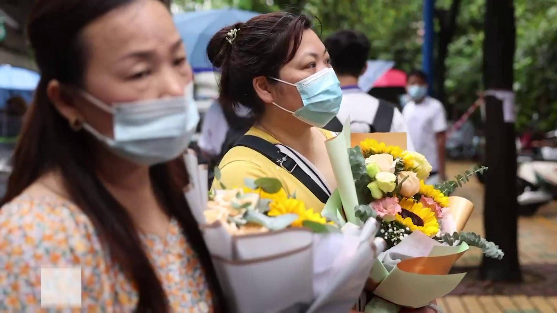 部分高考生结束考试广州高考考点外家长们手捧鲜花犹如花海