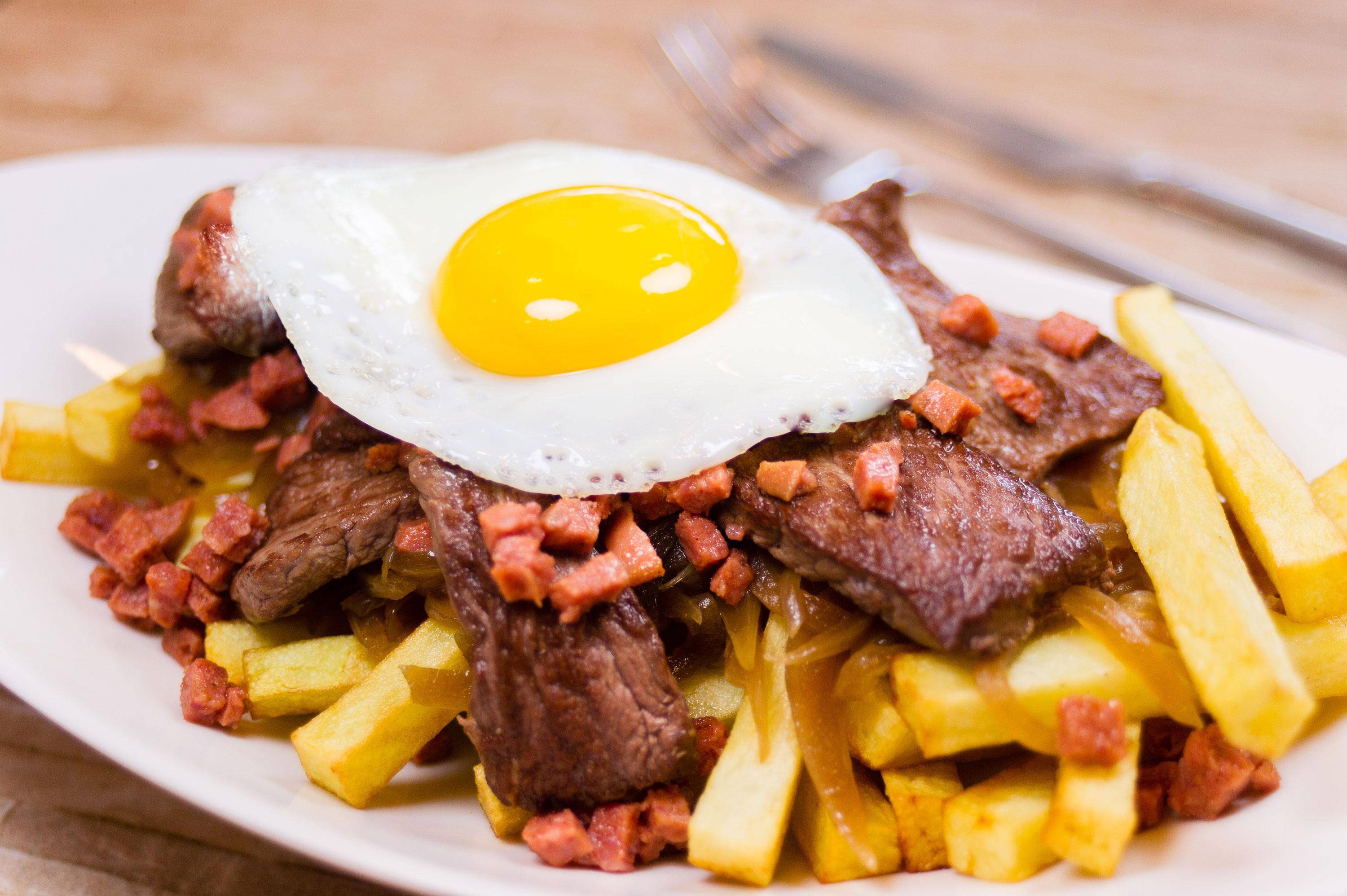 chorrillana(或bistec a la chorrillana)是一种流行的智利菜,主要