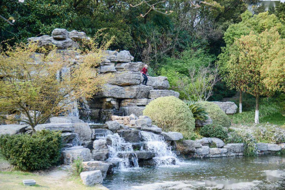 旁边长廊供游人小憩;北端小广场高低错落的千层石叠,瀑布沿着叠石水分