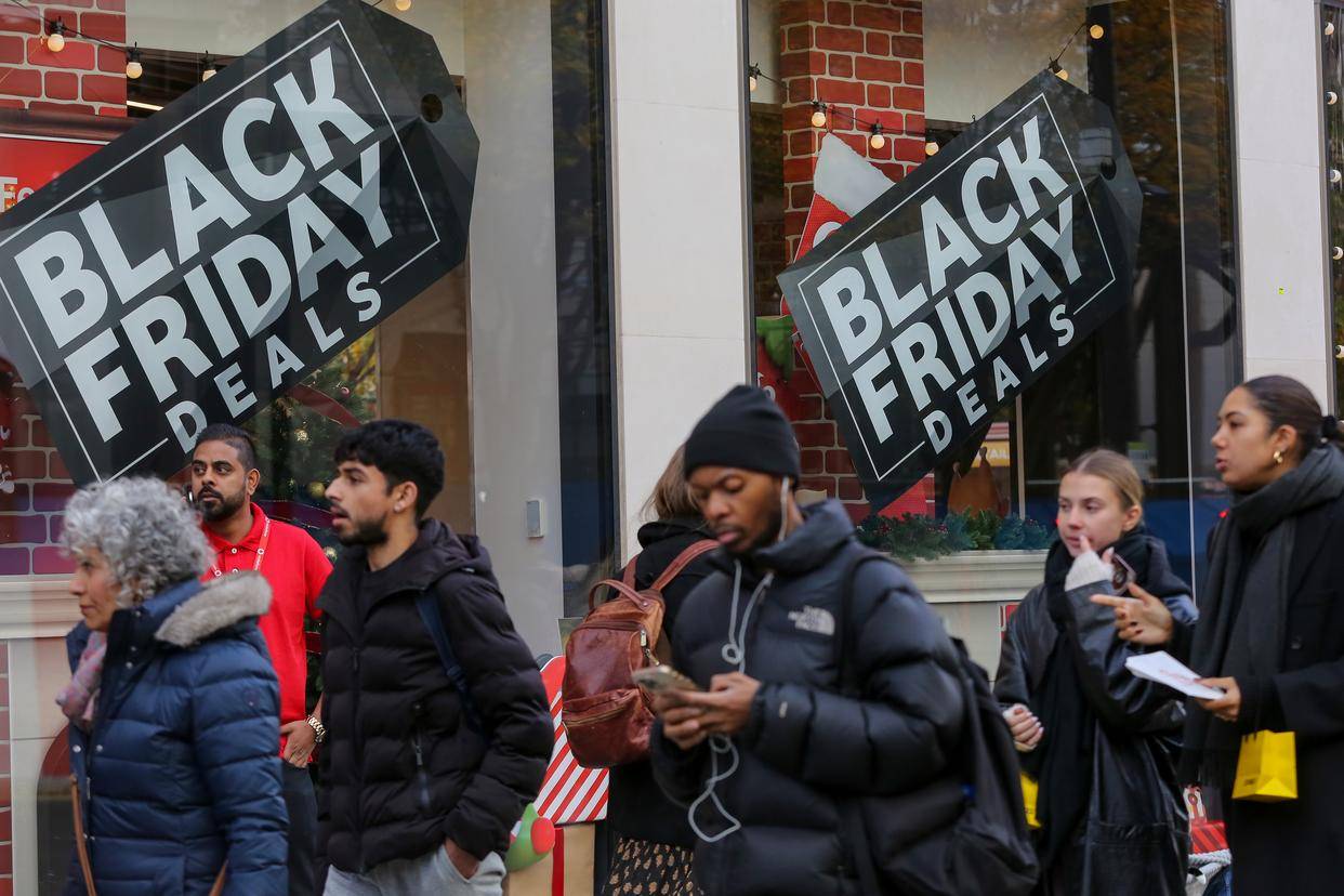 在英国伦敦牛津街,人们走过"黑色星期五"促销广告牌